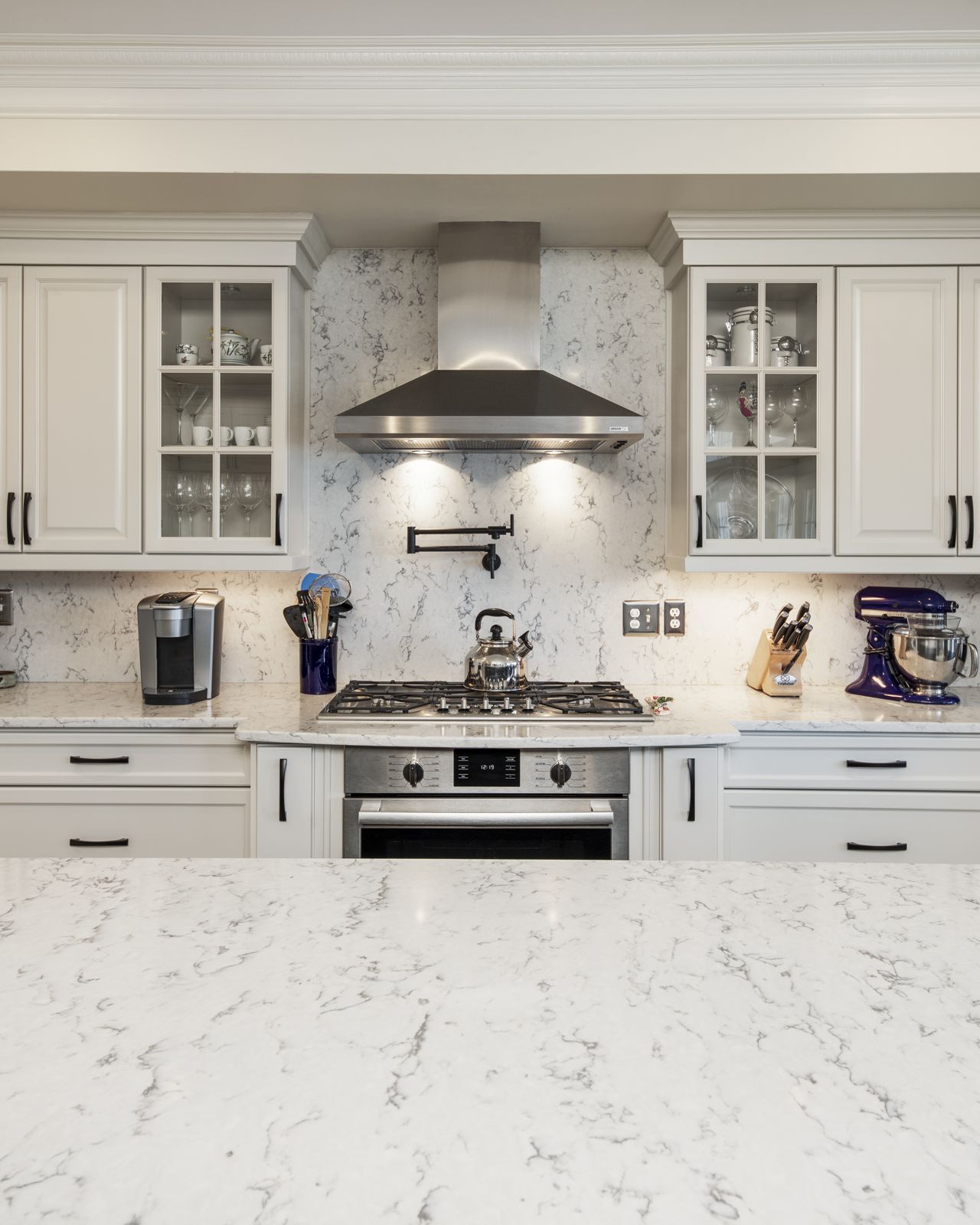 Range with marble backsplash and painted cabinetry